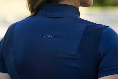 Person im Freien in einem EquiAttire Baselayer mit kurzen Ärmeln – marineblau, Logo sichtbar, von hinten gesehen.